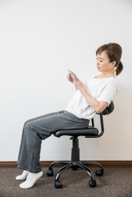 椅子に座ってスマホを見る女性
